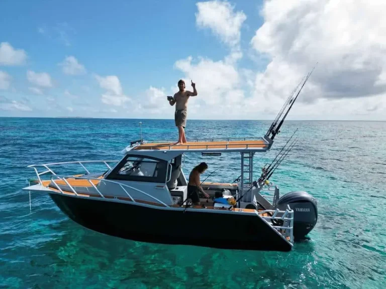 Angler on the bow of a plate aluminium boat over clear water