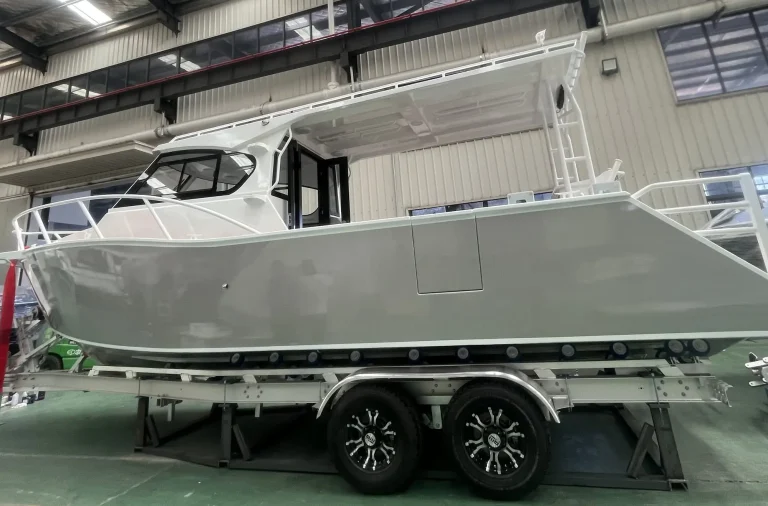 Bare aluminium hardtop boat on a trailer at the factory