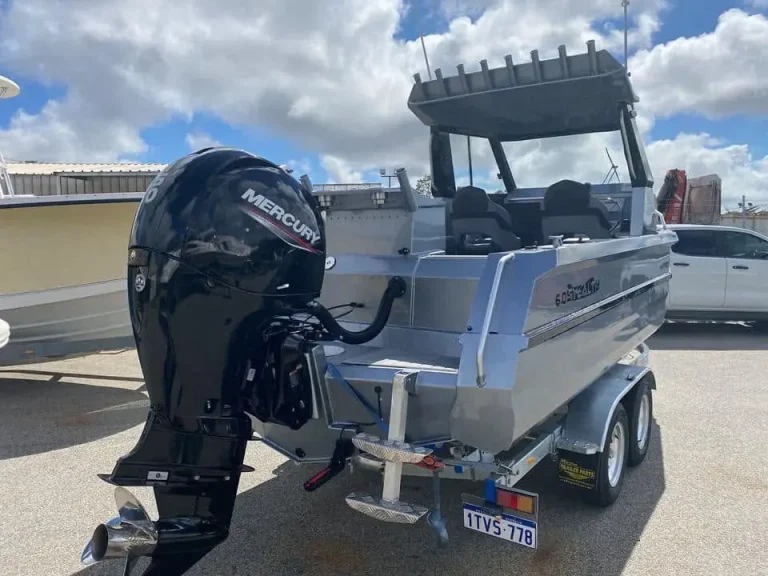 Bare aluminium hardtop boat with outboard on a trailer