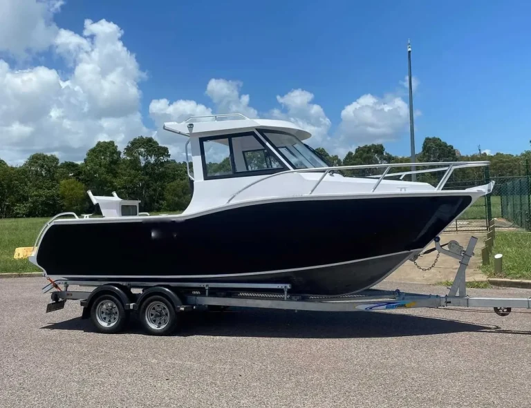 Black hulled plate aluminium cabin boat on a tandem trailer