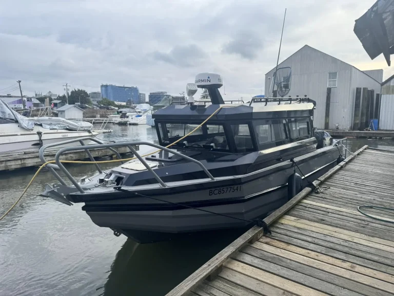 Black plate aluminium cabin boat berthed at a boat shed