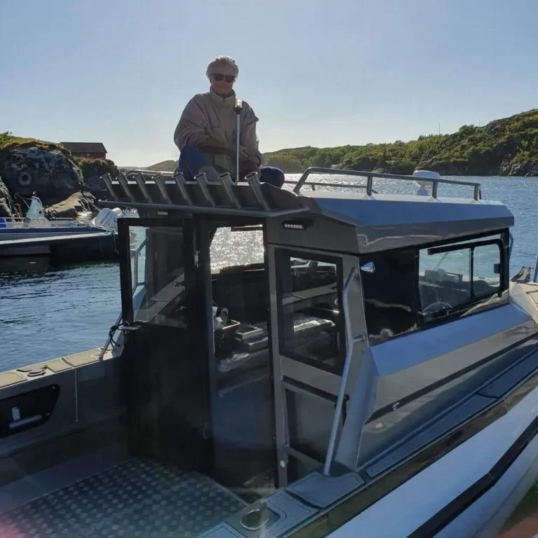 Black plate aluminium cabin boat idling near a rocky shoreline