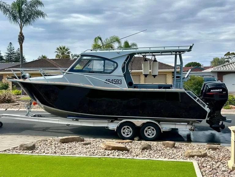 Black plate aluminium hardtop boat on a trailer at a house