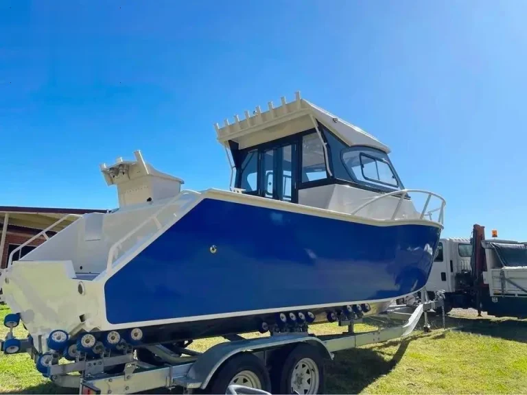 Blue plate aluminium hardtop boat on a trailer on grass