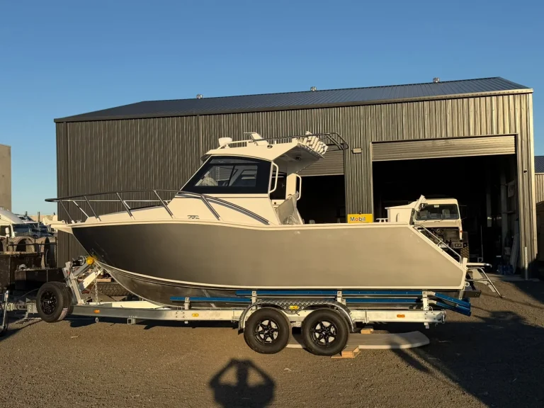 Champagne plate aluminium hardtop boat outside a shed