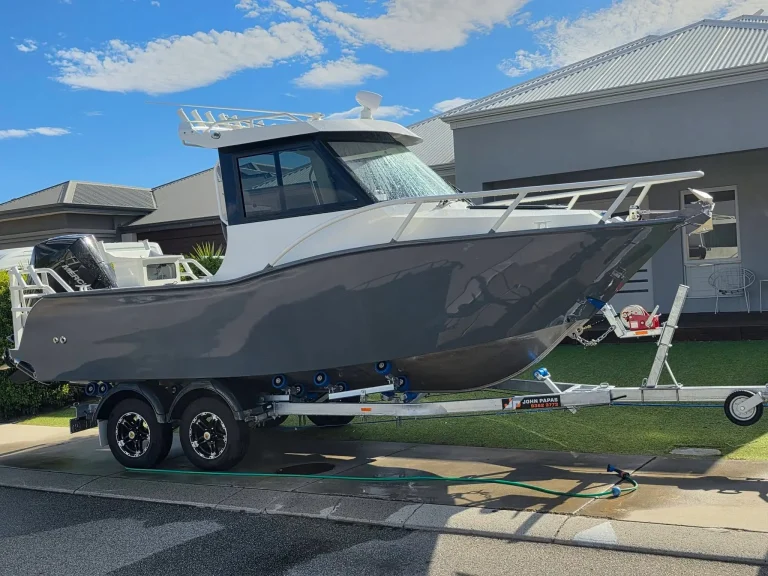 Grey plate aluminium hardtop boat on a trailer at home