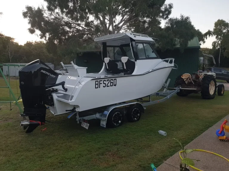 Grey plate aluminium hardtop boat on a trailer in a yard