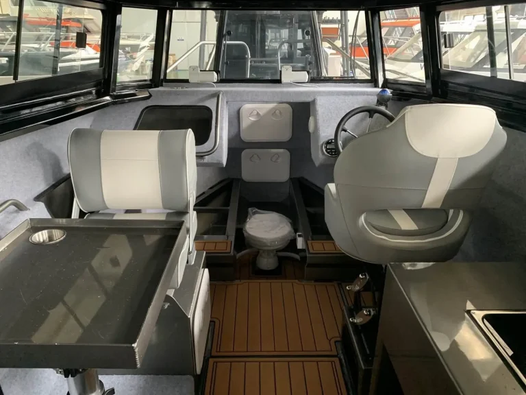 Helm station with twin bucket seats and side door inside a cabin boat