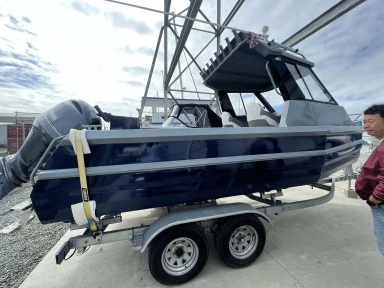 Navy plate aluminium hardtop boat on a trailer at a workshop