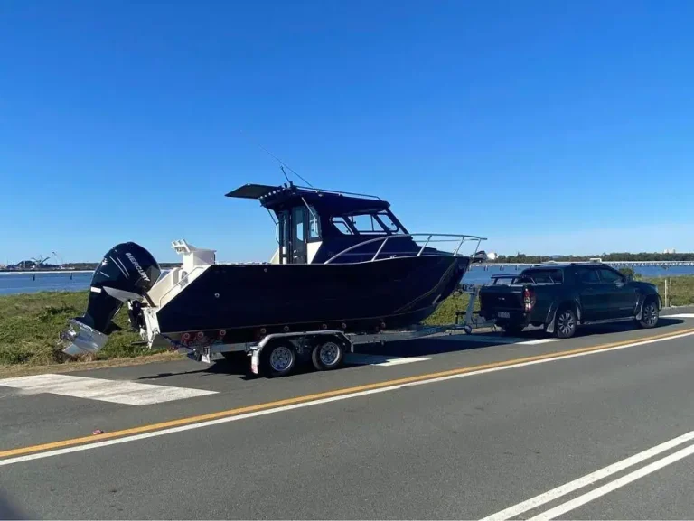 Navy plate aluminium hardtop boat under tow on the highway