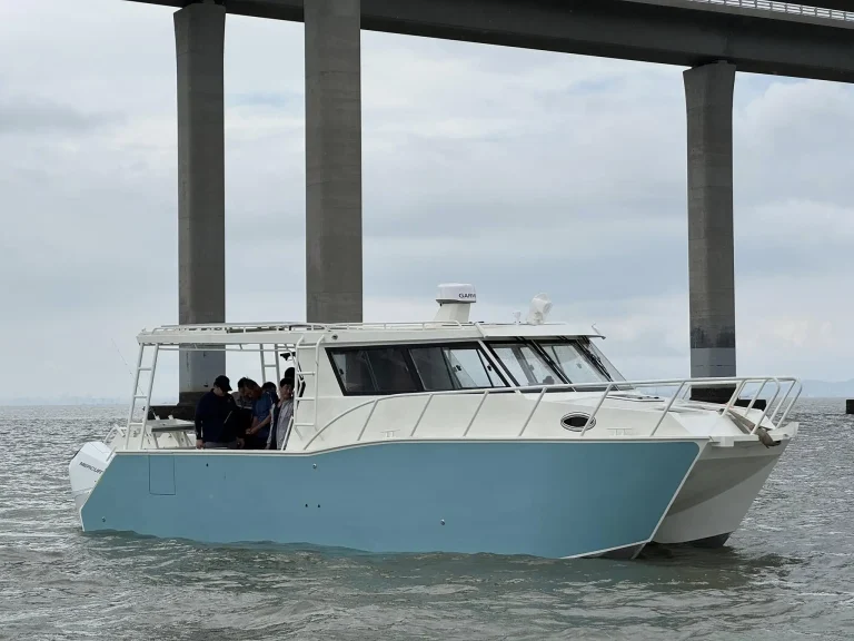 Pale blue plate aluminium work boat under a bridge