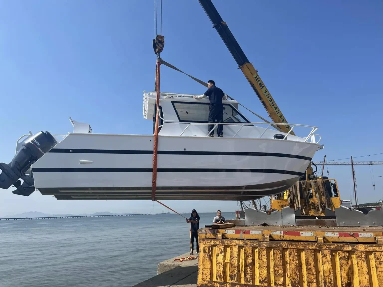 Plate aluminium boat being lifted by crane at the wharf