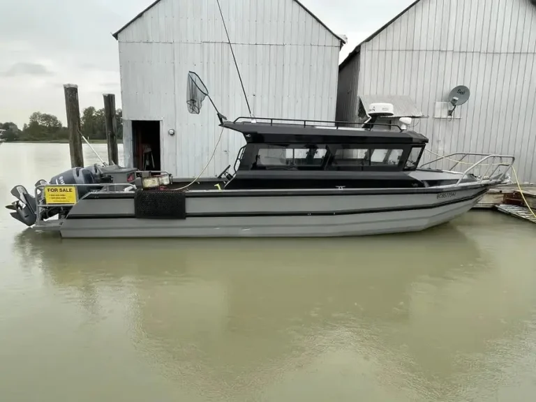Plate aluminium cabin boat moored beside a boat shed