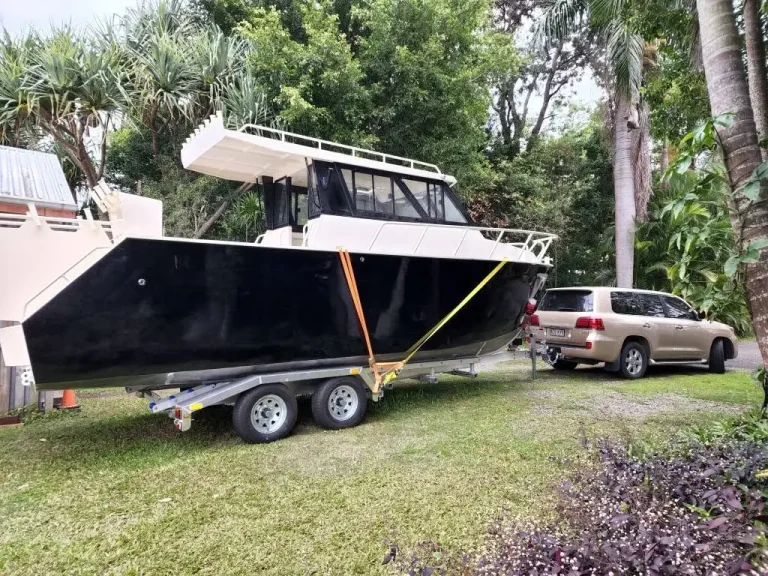 Plate aluminium hardtop boat on a trailer under trees
