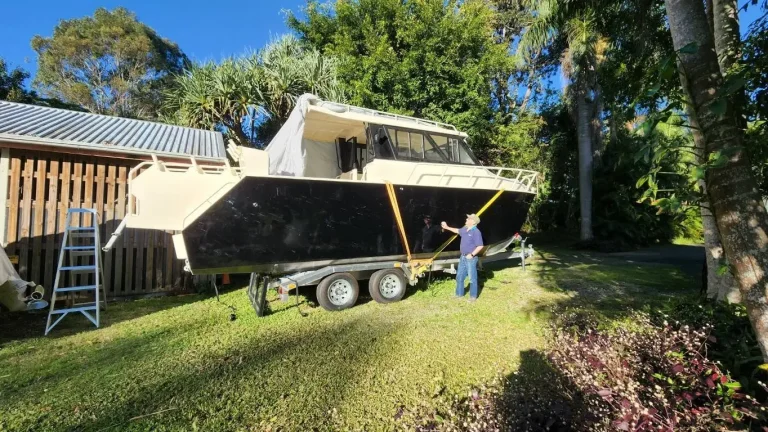 Plate aluminium hardtop boat stored beside a shed