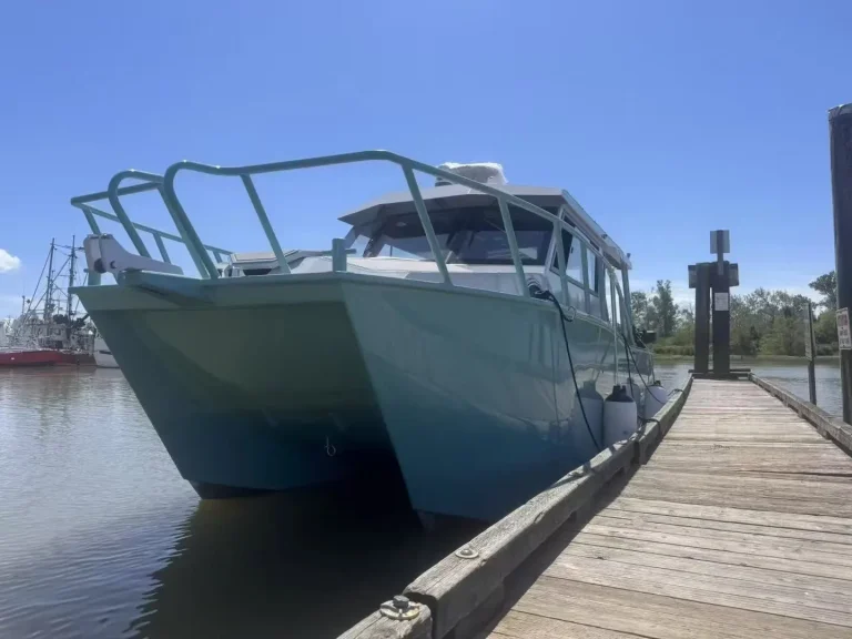 Plate aluminium work boat alongside a timber jetty
