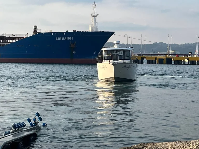 Plate aluminium work boat beside a cargo ship