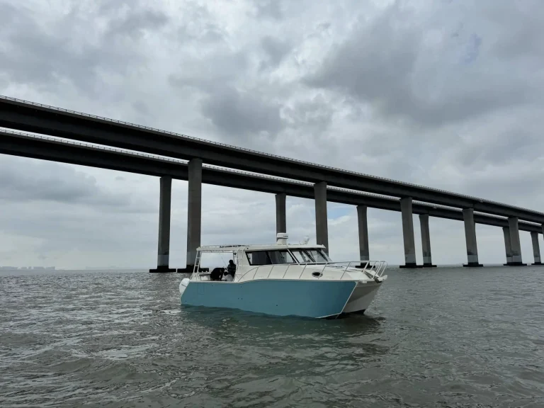 Plate aluminium work boat on open water by a bridge