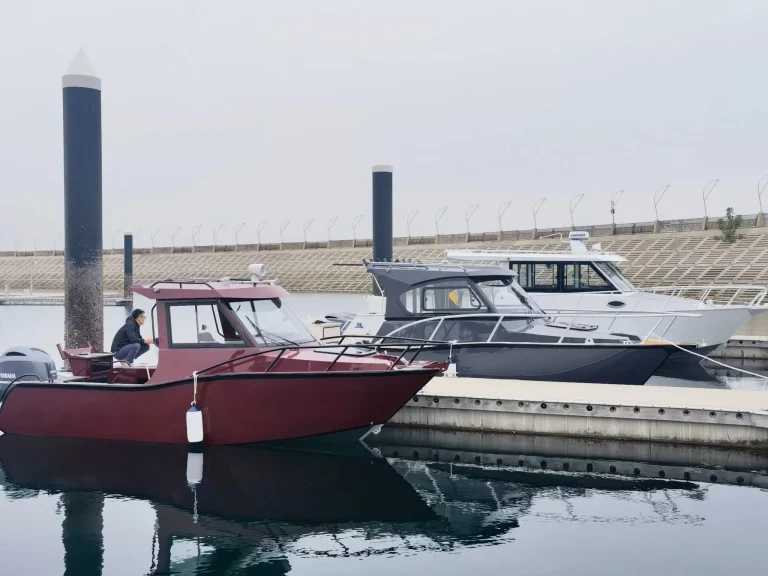 Red and charcoal plate aluminium cabin boats moored alongside a breakwater