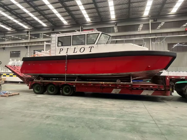 Red and white pilot boat on a low loader