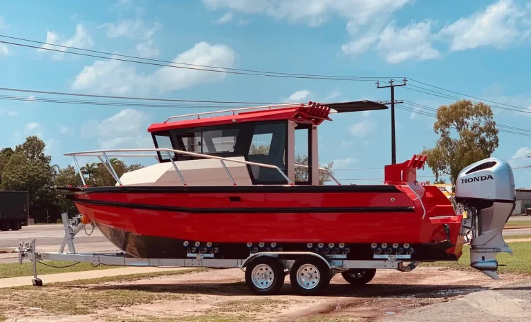 Red plate aluminium work boat with crane on a trailer