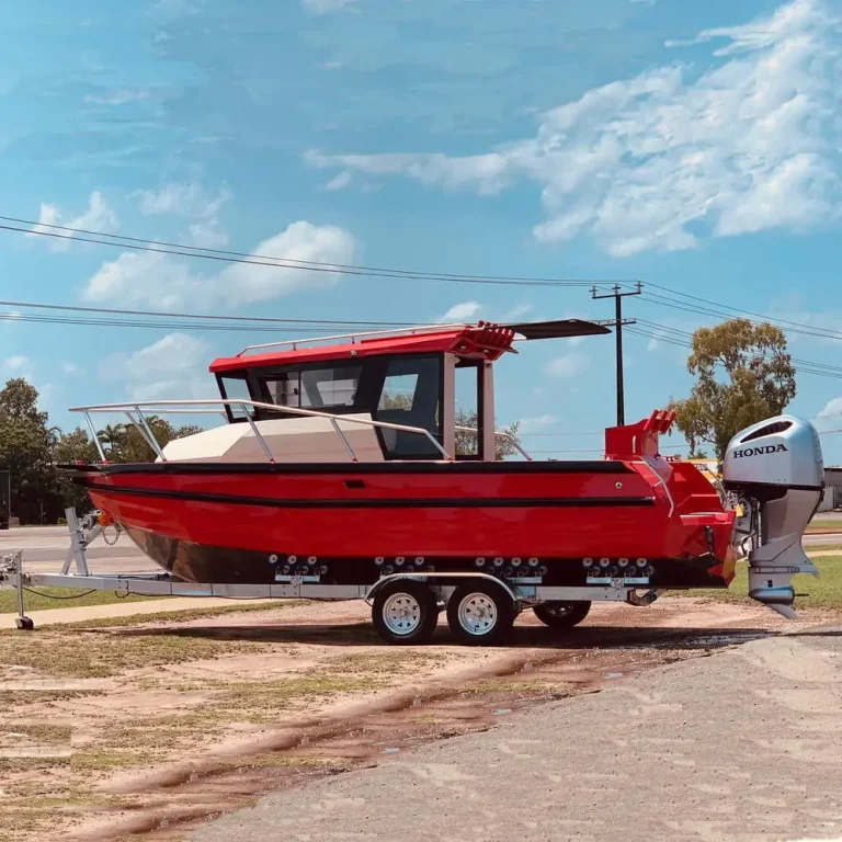 Red plate aluminium work boat with crane on a trailer