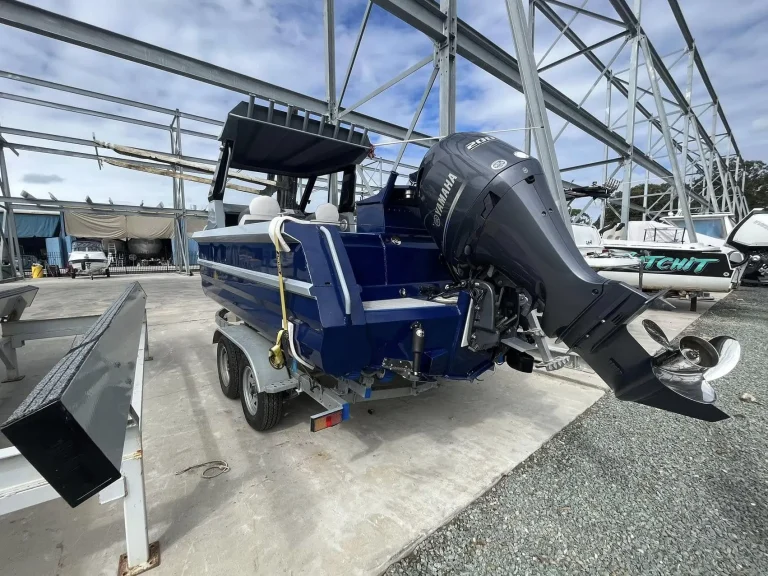 Stern of a navy hardtop boat with outboard on a trailer