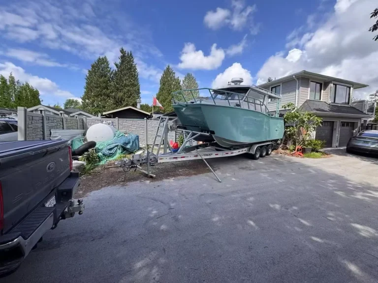 Teal plate aluminium hardtop boat on a trailer at a house