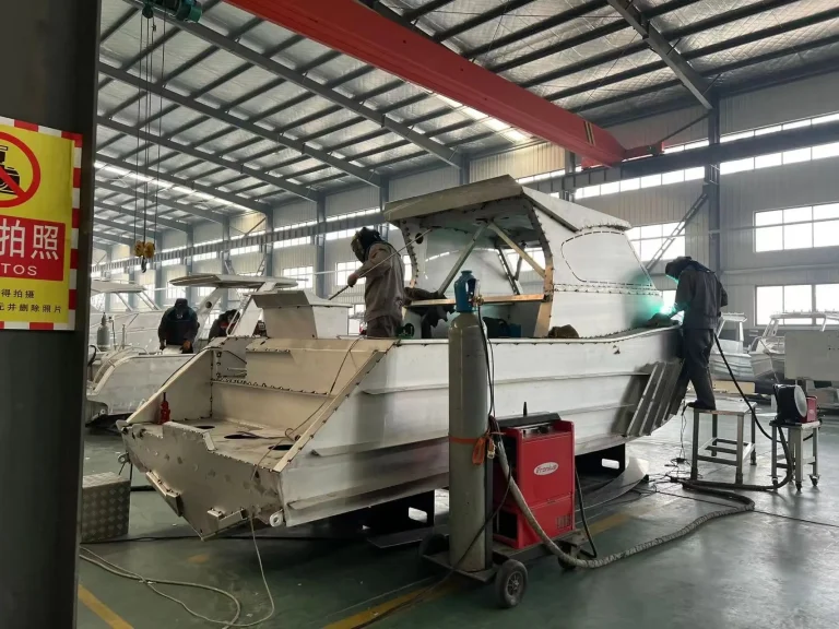Welder working on a plate aluminium hull in the factory