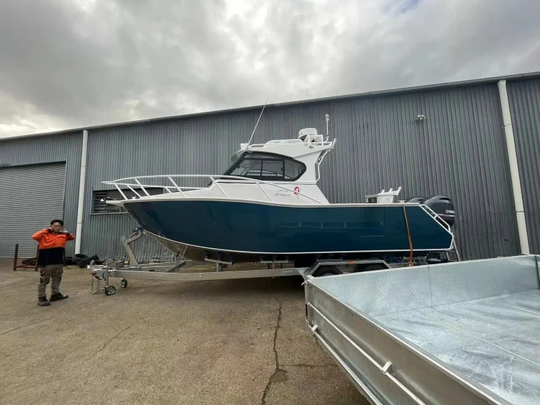 White and teal plate aluminium cabin boat at a shed