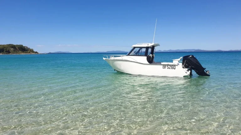 White plate aluminium cabin boat anchored over sand