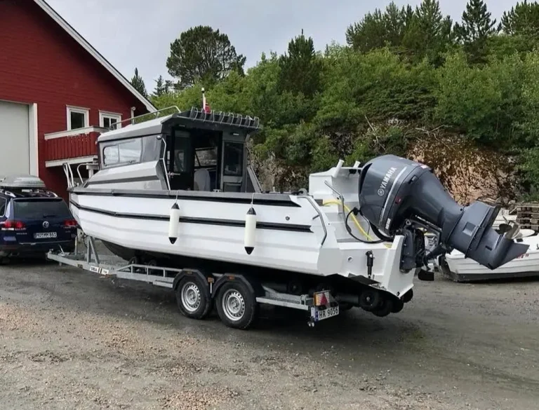White plate aluminium hardtop boat on a trailer outside the shed