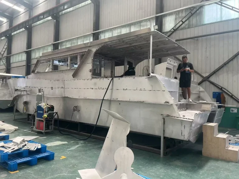 Worker finishing a large aluminium hull in the factory