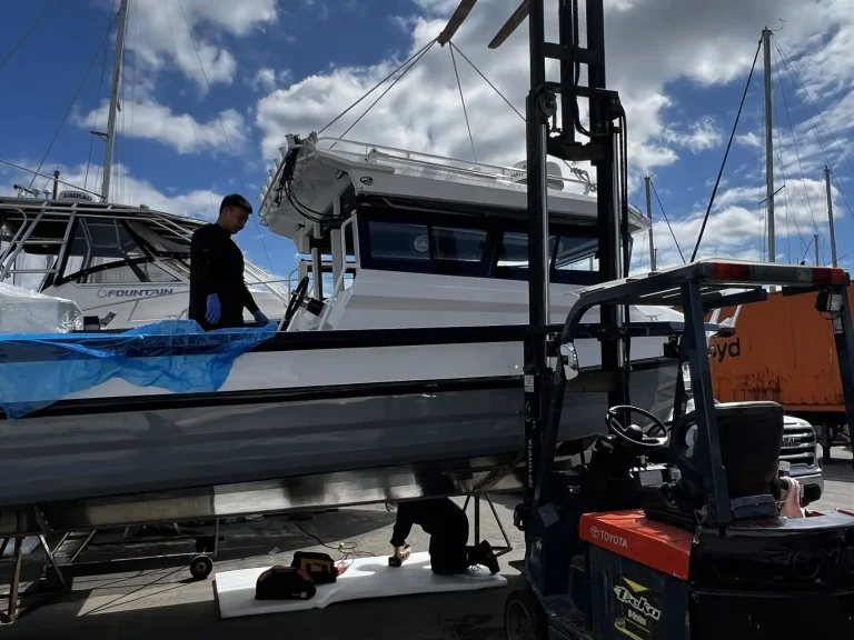 Worker on a plate aluminium hull under a boat lift